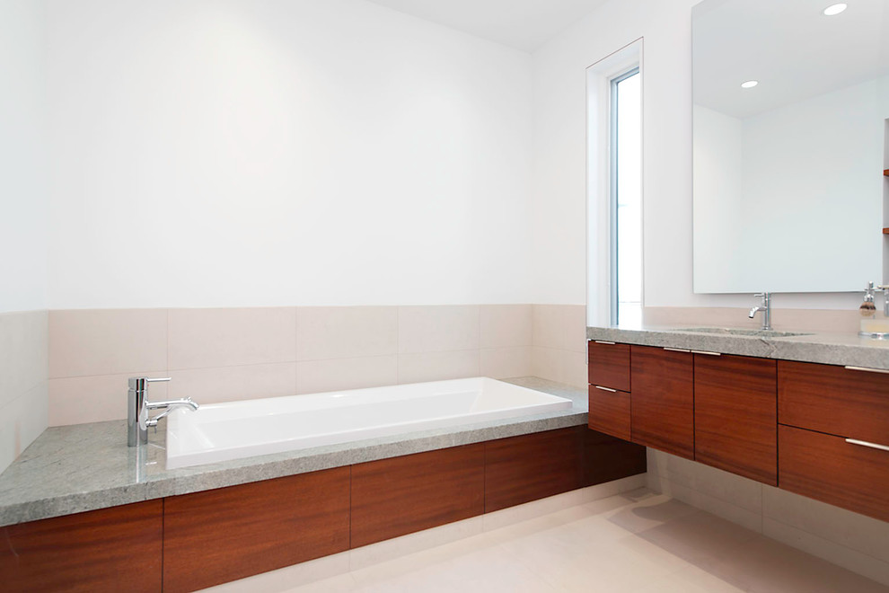 Ispirazione per una stanza da bagno padronale contemporanea di medie dimensioni con ante lisce, ante in legno bruno, vasca da incasso, piastrelle beige, piastrelle in gres porcellanato, pareti bianche, pavimento con piastrelle in ceramica, lavabo sottopiano, top in cemento e pavimento beige