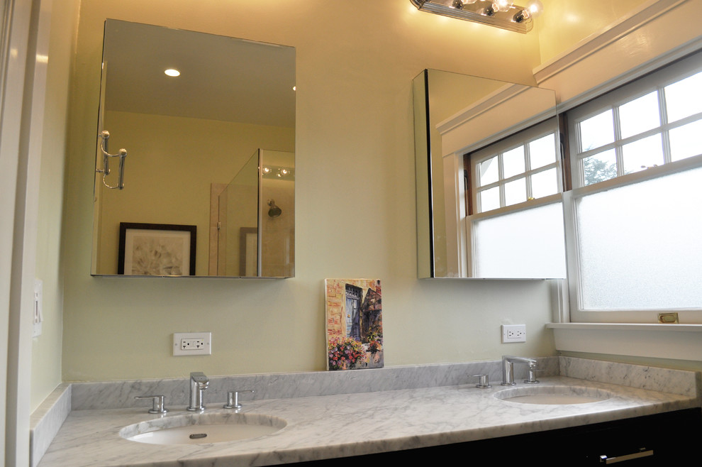 Cette image montre une salle de bain principale traditionnelle en bois foncé de taille moyenne avec un placard en trompe-l'oeil, une douche d'angle, WC séparés, un carrelage beige, un carrelage de pierre, un mur gris, un sol en travertin, un lavabo encastré et un plan de toilette en marbre.