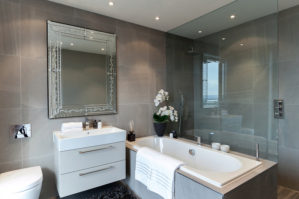 Small contemporary family bathroom in London with a built-in shower, a wall mounted toilet and grey tiles.