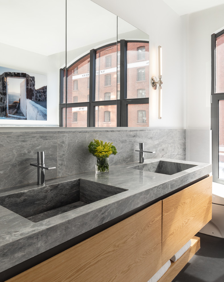 This is an example of a large contemporary ensuite bathroom in New York with flat-panel cabinets, medium wood cabinets, marble tiles, white walls, slate flooring, an integrated sink, marble worktops, black floors, grey worktops, a freestanding bath, a corner shower and a hinged door.