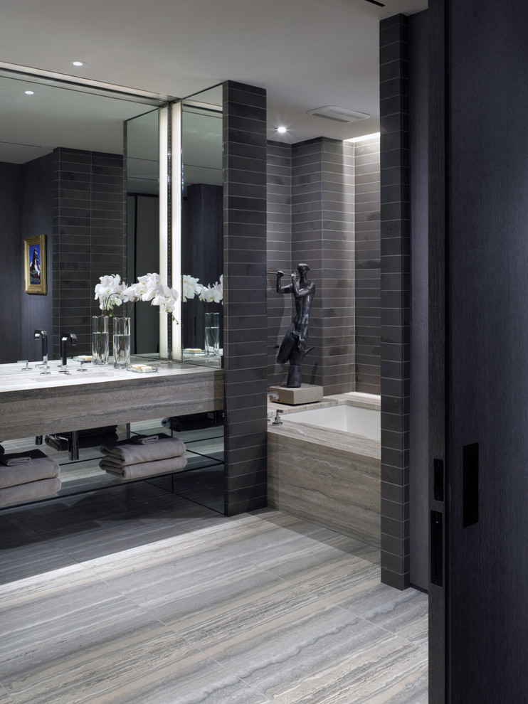 На фото: большая главная ванная комната в стиле модернизм с врезной раковиной, полновстраиваемой ванной, душем в нише, инсталляцией, серой плиткой, серыми стенами, полом из известняка и открытыми фасадами с