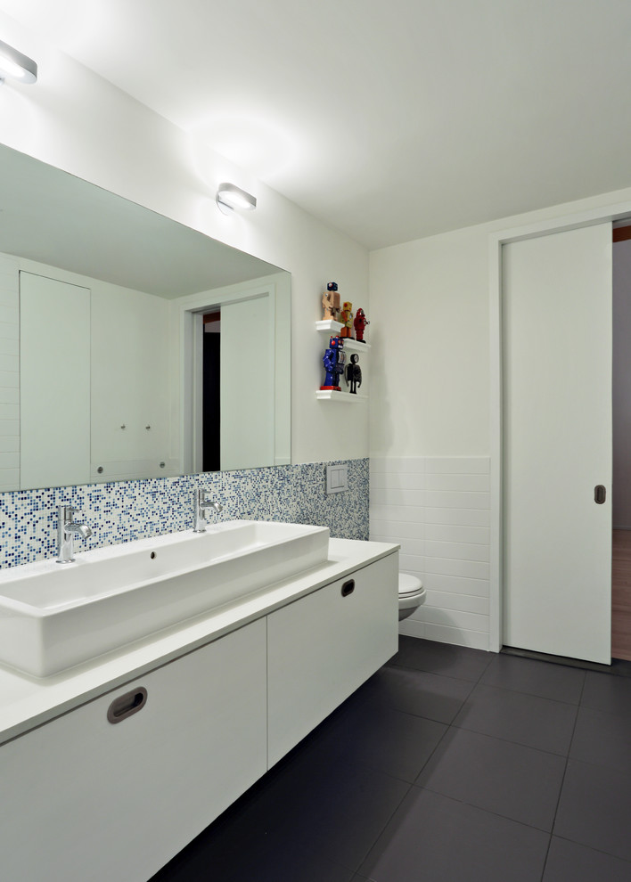 Inredning av ett modernt stort en-suite badrum, med släta luckor, vita skåp, ett badkar i en alkov, en dusch i en alkov, blå kakel, vit kakel, mosaik, vita väggar, klinkergolv i porslin, ett avlångt handfat och bänkskiva i akrylsten