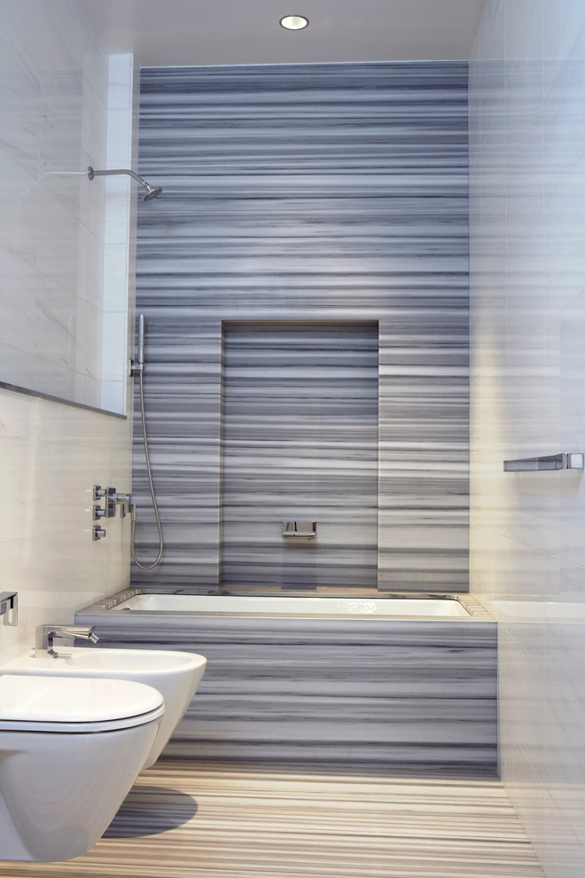 Inredning av ett modernt badrum, med ett undermonterat badkar, en dusch/badkar-kombination, stenhäll och grå kakel