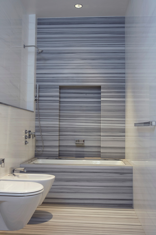 Modernes Badezimmer mit Badewanne in Nische, Duschbadewanne, grauen Fliesen, Steinplatten und weißer Wandfarbe in New York