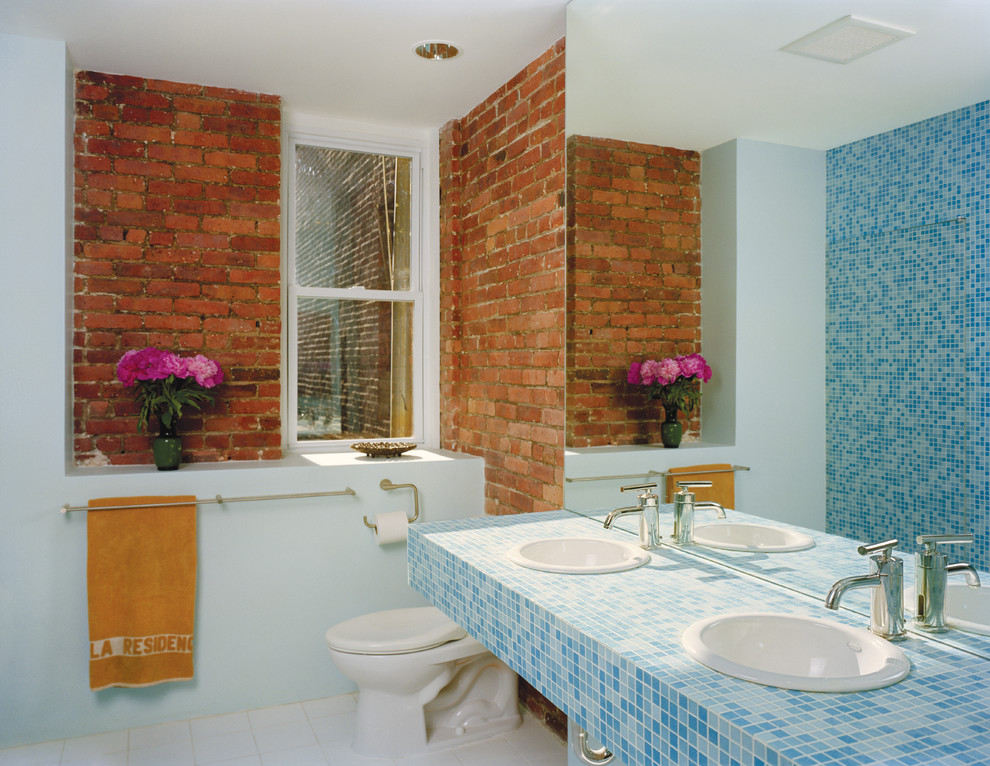 Imagen de cuarto de baño principal actual de tamaño medio con sanitario de una pieza, paredes azules, suelo de baldosas de porcelana, encimera de azulejos y encimeras azules