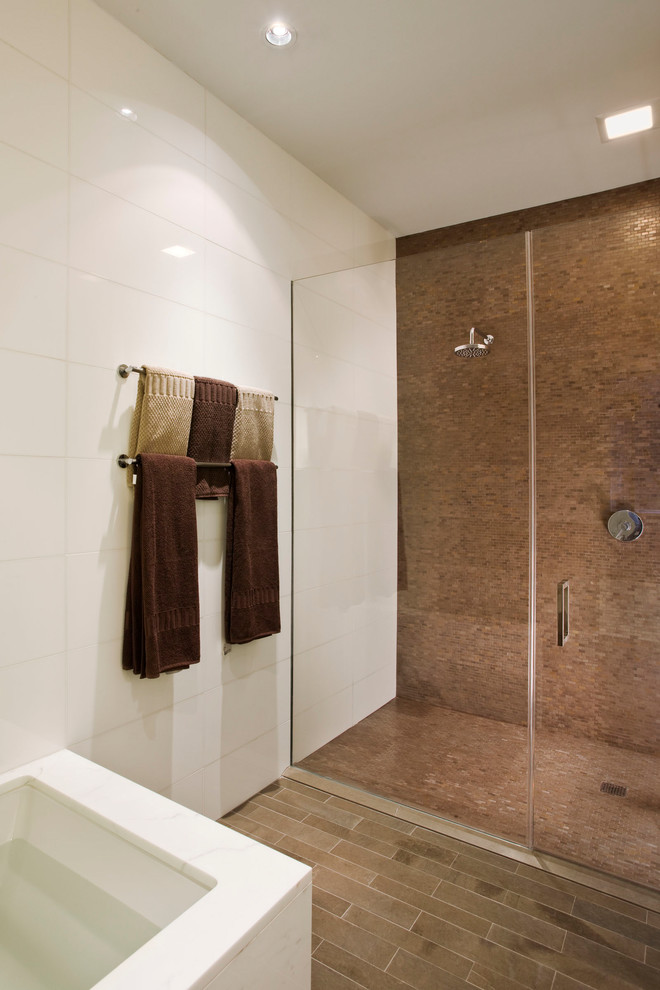 This is an example of a medium sized contemporary ensuite bathroom in New York with flat-panel cabinets, dark wood cabinets, an alcove bath, an alcove shower, brown tiles, mosaic tiles, white walls, porcelain flooring, a submerged sink, solid surface worktops, brown floors, a hinged door and white worktops.