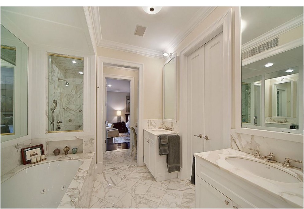 Cette image montre une salle de bain traditionnelle avec un lavabo encastré, un placard avec porte à panneau encastré, des portes de placard blanches, un plan de toilette en marbre, une baignoire encastrée, une douche d'angle et un carrelage de pierre.