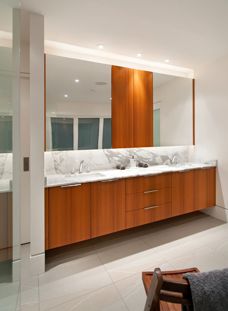 Modelo de cuarto de baño actual con lavabo bajoencimera, armarios con paneles lisos, puertas de armario de madera oscura y paredes blancas