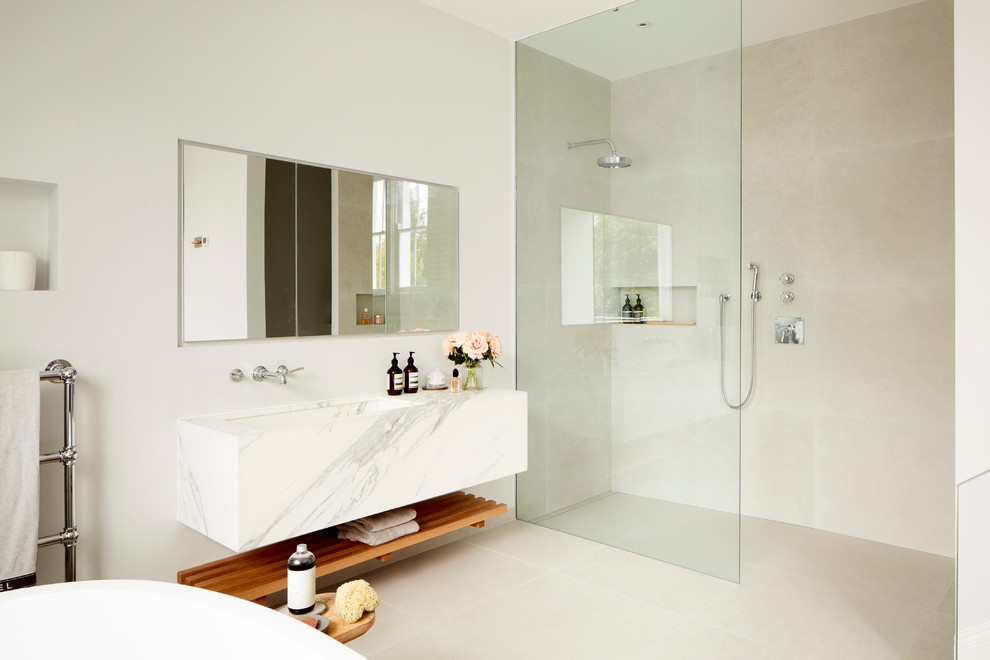 Immagine di una stanza da bagno design con vasca freestanding, doccia aperta e top in marmo