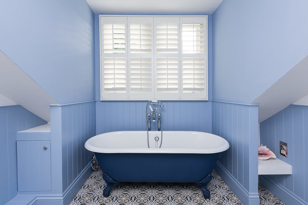 Klassisk inredning av ett mellanstort badrum för barn, med ett badkar med tassar och blå väggar