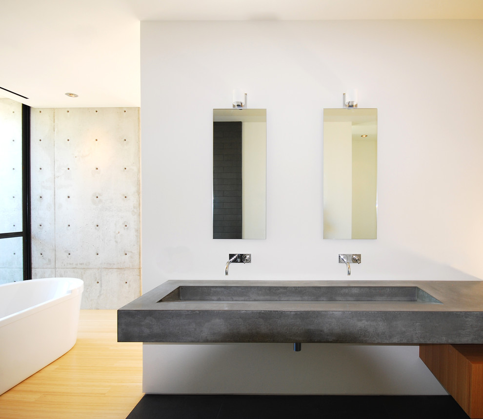 Example of a minimalist freestanding bathtub design in Phoenix with concrete countertops and a trough sink