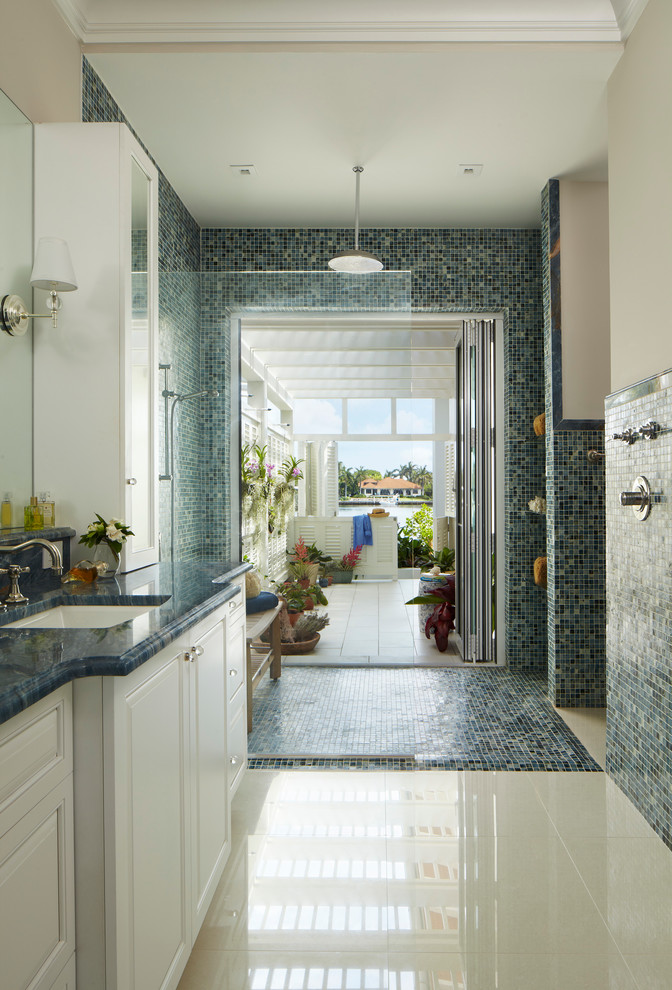 マイアミにあるトロピカルスタイルのおしゃれな浴室 (アンダーカウンター洗面器、レイズドパネル扉のキャビネット、白いキャビネット、オープン型シャワー、青いタイル、オープンシャワー、青い洗面カウンター) の写真