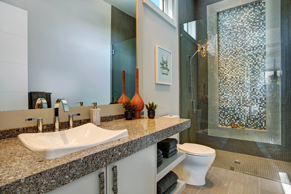 他の地域にあるトロピカルスタイルのおしゃれなバスルーム (浴槽なし) (フラットパネル扉のキャビネット、グレーのキャビネット、グレーのタイル、開き戸のシャワー) の写真