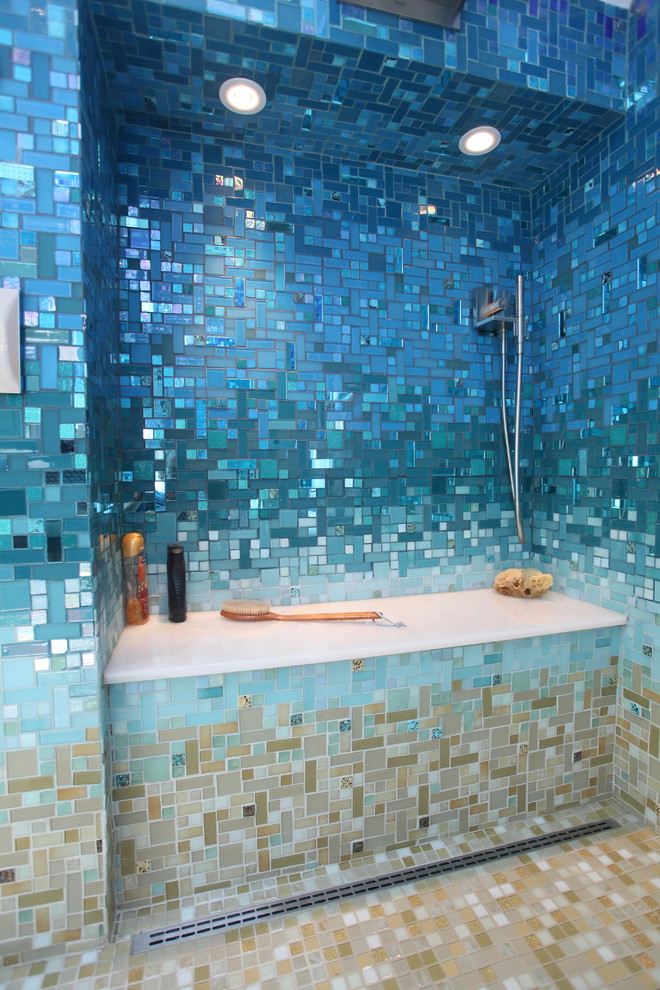 Foto på ett stort tropiskt en-suite badrum, med släta luckor, svarta skåp, ett platsbyggt badkar, en öppen dusch, en toalettstol med hel cisternkåpa, blå kakel, glaskakel, blå väggar, klinkergolv i keramik, ett piedestal handfat, bänkskiva i akrylsten, beiget golv och med dusch som är öppen