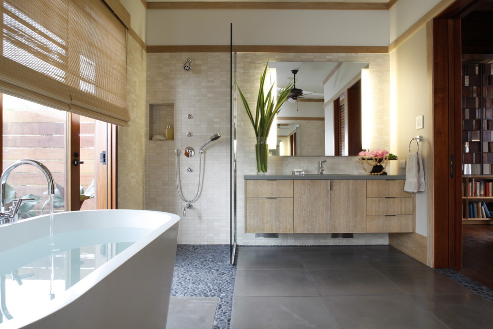 Inredning av ett badrum, med ett fristående badkar, en öppen dusch, klinkergolv i småsten och med dusch som är öppen