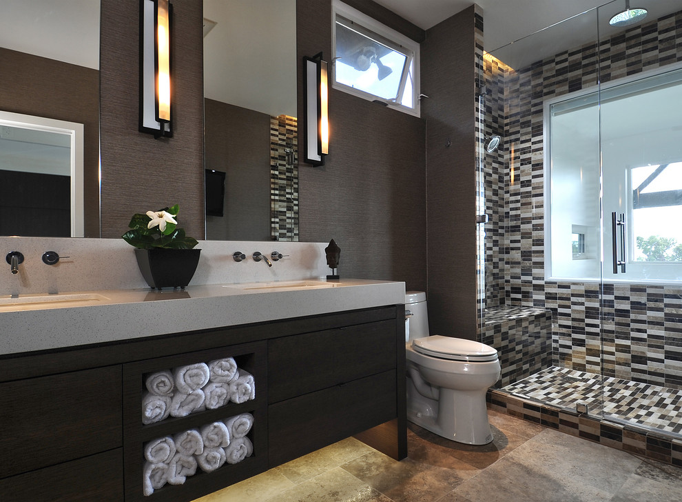 Photo of a contemporary ensuite bathroom in Hawaii with flat-panel cabinets, mosaic tiles, a submerged sink, dark wood cabinets, engineered stone worktops, a walk-in shower, a one-piece toilet, brown tiles, brown walls, travertine flooring, a hinged door and brown floors.