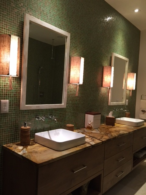Foto på ett stort tropiskt en-suite badrum, med släta luckor, bruna skåp, ett platsbyggt badkar, en hörndusch, grön kakel, mosaik, gröna väggar, kalkstensgolv, ett avlångt handfat, bänkskiva i onyx, beiget golv och med dusch som är öppen