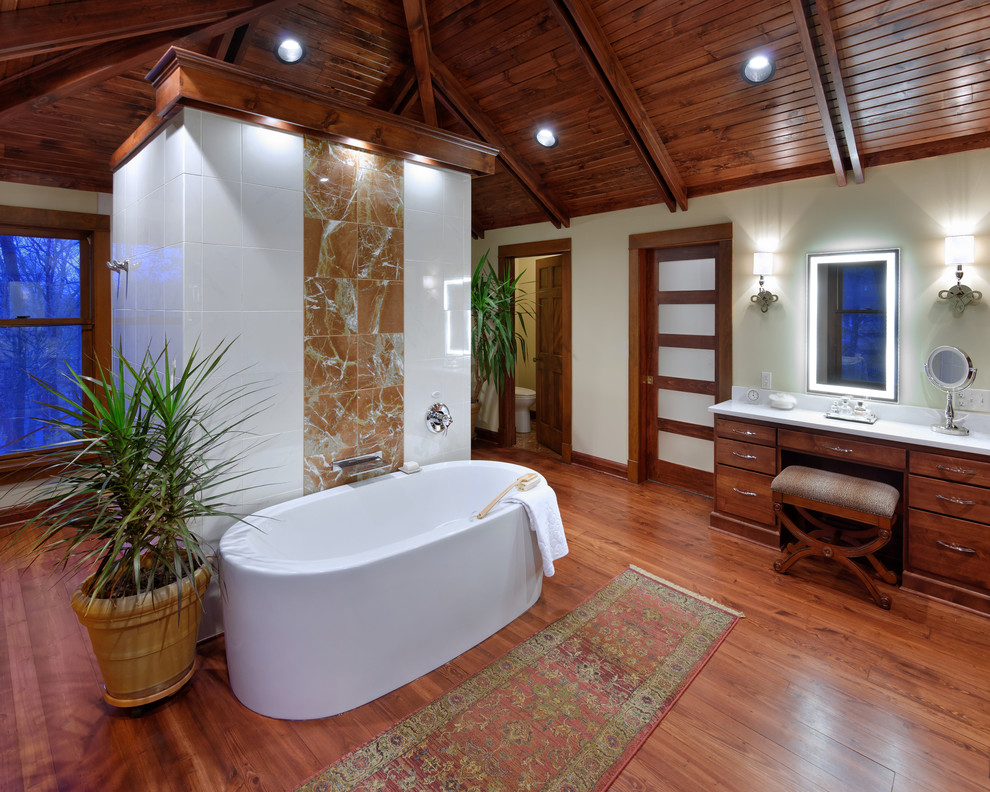 Ispirazione per una stanza da bagno tropicale con ante lisce, ante in legno scuro, vasca freestanding, pareti bianche e pavimento in legno massello medio