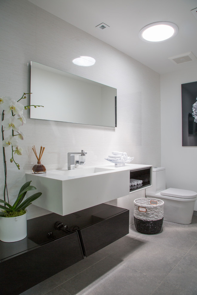 Foto på ett mellanstort funkis en-suite badrum, med ett fristående badkar, en dusch i en alkov, betonggolv, grått golv, dusch med skjutdörr, släta luckor, vita skåp, en toalettstol med separat cisternkåpa, vita väggar, ett integrerad handfat och bänkskiva i akrylsten