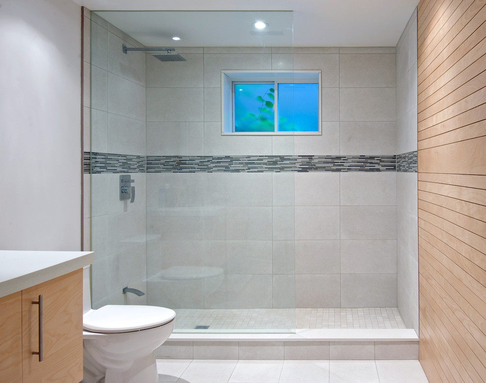 Пример оригинального дизайна: ванная комната среднего размера в современном стиле с монолитной раковиной, плоскими фасадами, светлыми деревянными фасадами, столешницей из искусственного кварца, открытым душем, унитазом-моноблоком, серой плиткой, керамогранитной плиткой, серыми стенами, полом из керамогранита и душевой кабиной