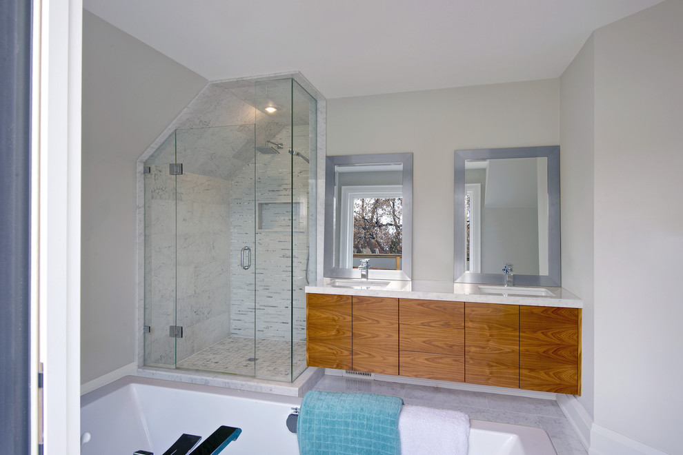 Inredning av ett modernt mellanstort en-suite badrum, med ett integrerad handfat, släta luckor, skåp i mellenmörkt trä, bänkskiva i kvarts, ett fristående badkar, en öppen dusch, en toalettstol med hel cisternkåpa, grå kakel, porslinskakel, grå väggar och klinkergolv i porslin