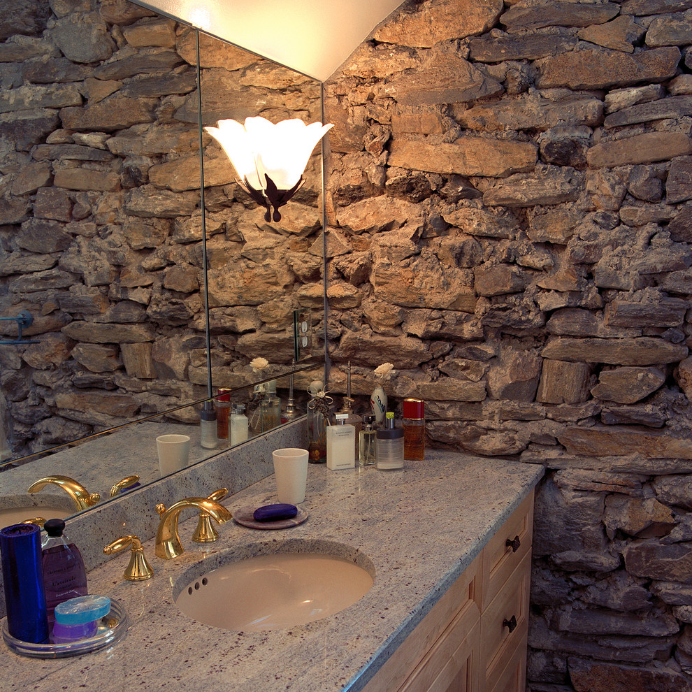 Diseño de cuarto de baño rústico con lavabo bajoencimera, armarios con paneles con relieve, puertas de armario de madera clara, encimera de granito y paredes grises