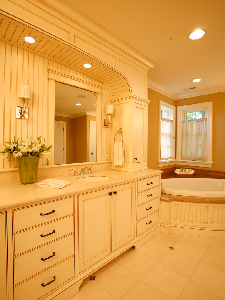 Ejemplo de cuarto de baño tradicional con lavabo bajoencimera, armarios con paneles empotrados, puertas de armario blancas, bañera esquinera, ducha doble y paredes beige