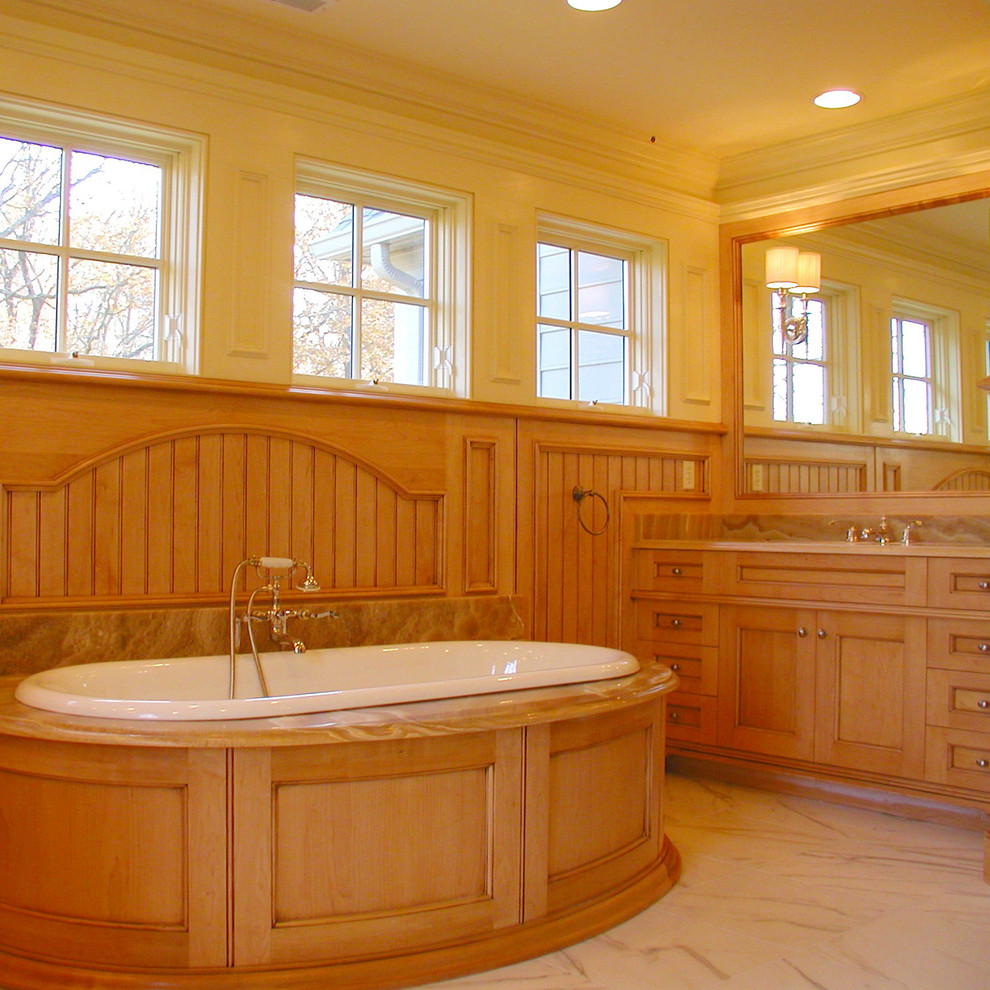 Imagen de cuarto de baño tradicional con lavabo bajoencimera, armarios con paneles empotrados, puertas de armario de madera clara, encimera de mármol, bañera encastrada, paredes blancas y suelo de mármol