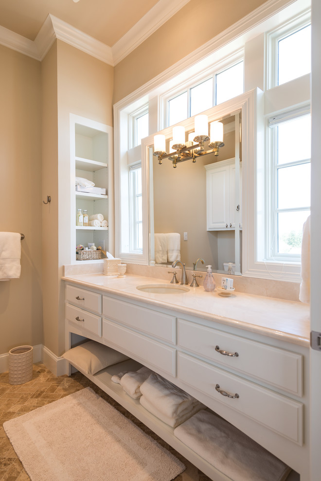 На фото: ванная комната в классическом стиле с врезной раковиной, белыми фасадами, бежевыми стенами и фасадами с выступающей филенкой