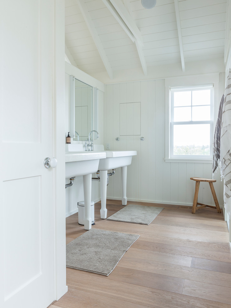 Imagen de cuarto de baño costero con lavabo tipo consola, paredes blancas, suelo de madera en tonos medios y suelo beige