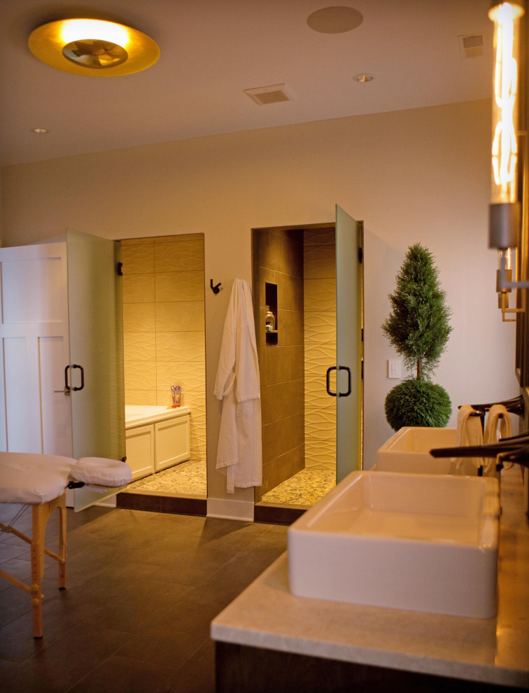 Cette image montre une grande salle de bain craftsman avec des portes de placard marrons, une baignoire posée, un carrelage beige, des carreaux de céramique, un mur beige, un sol en carrelage de céramique, une vasque, un sol marron, une cabine de douche à porte battante et un plan de toilette beige.