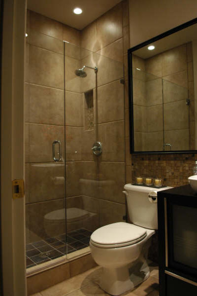 Cette photo montre une petite douche en alcôve en bois foncé avec une vasque, un placard à porte vitrée, un plan de toilette en bois, un carrelage marron, des carreaux de porcelaine, un mur beige et un sol en carrelage de porcelaine.
