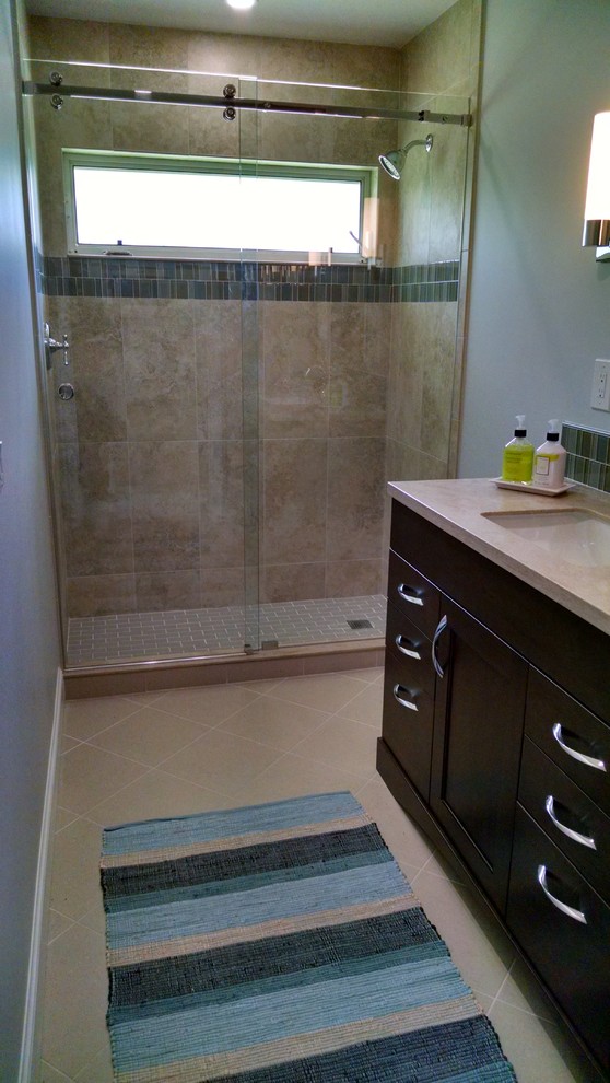 Foto på ett mellanstort vintage beige badrum med dusch, med luckor med infälld panel, skåp i mörkt trä, en dusch i en alkov, brun kakel, keramikplattor, grå väggar, klinkergolv i keramik, ett undermonterad handfat, bänkskiva i kvarts, beiget golv och dusch med skjutdörr