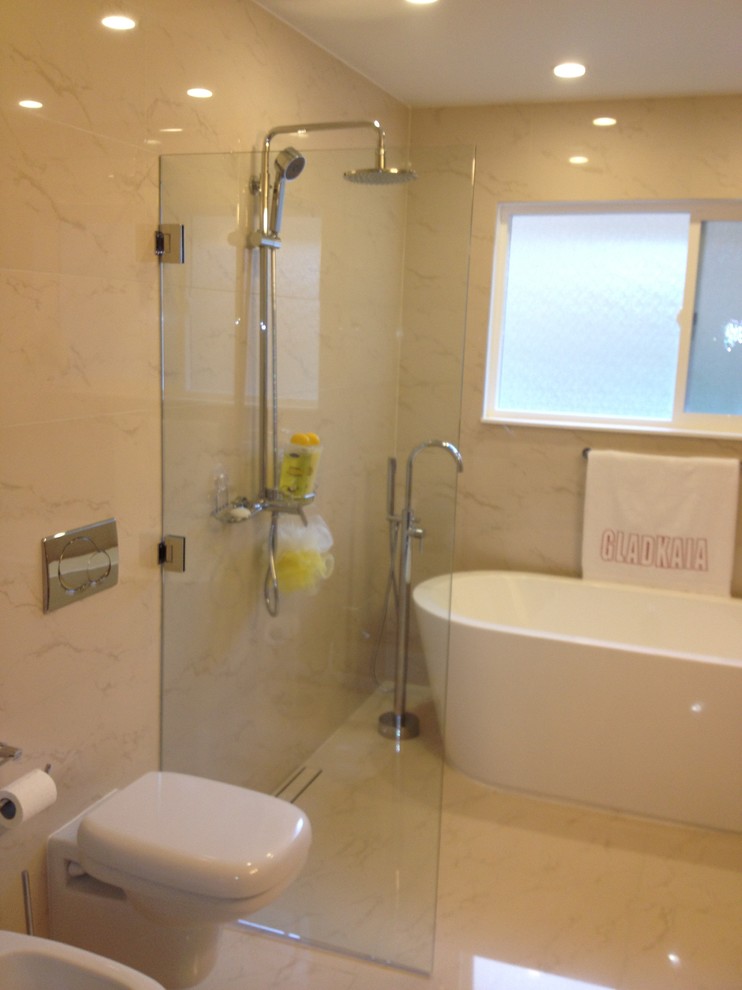 Immagine di una stanza da bagno padronale minimal di medie dimensioni con consolle stile comò, vasca freestanding, doccia aperta, WC monopezzo, piastrelle beige, lastra di pietra, pareti beige e pavimento in travertino