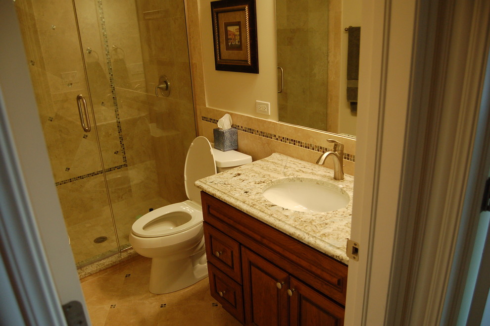 Foto di una stanza da bagno minimalista di medie dimensioni con lavabo sottopiano, ante con bugna sagomata, ante in legno scuro, top in marmo, doccia ad angolo, WC a due pezzi e piastrelle in pietra