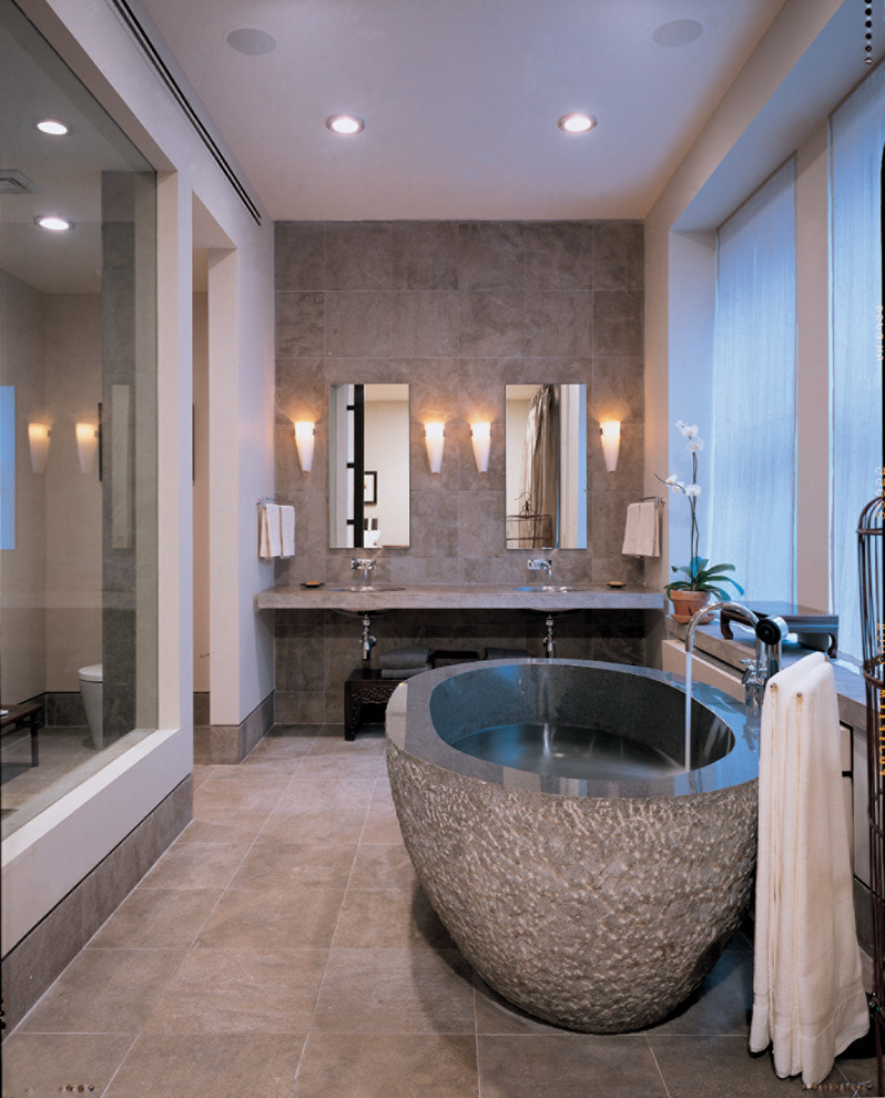 This is an example of a medium sized contemporary ensuite bathroom in Miami with a freestanding bath, a corner shower, a one-piece toilet, grey tiles, stone tiles, white walls, slate flooring, a submerged sink and solid surface worktops.