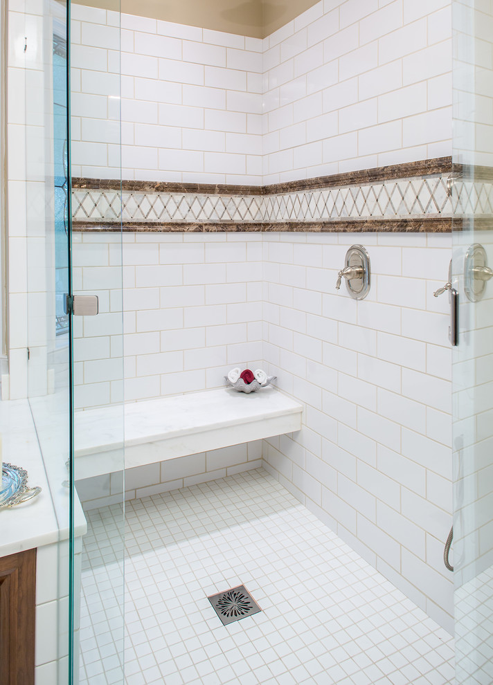 Cette image montre une grande salle de bain principale traditionnelle en bois foncé avec un placard avec porte à panneau surélevé, une baignoire encastrée, une douche d'angle, un mur beige, un sol en marbre, un lavabo encastré, un plan de toilette en marbre et un banc de douche.