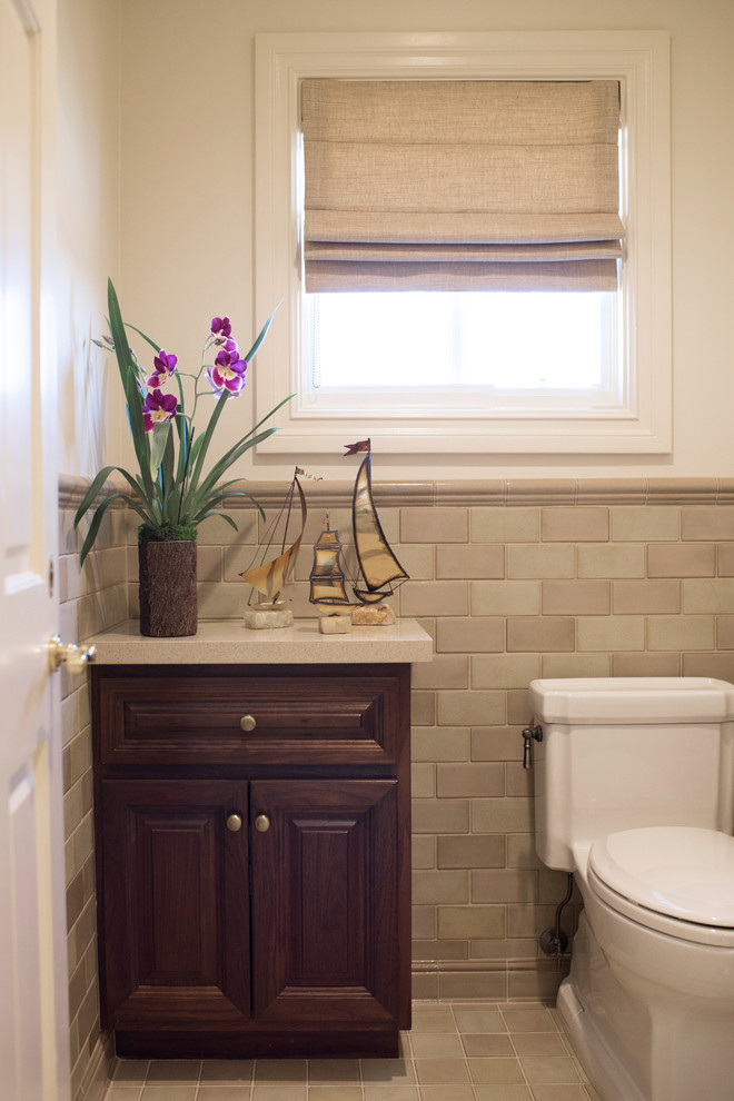 Photo of a large traditional ensuite bathroom in Los Angeles with raised-panel cabinets, dark wood cabinets, beige tiles, grey tiles, stone tiles, solid surface worktops, a built-in bath, a one-piece toilet, a submerged sink, white walls and ceramic flooring.