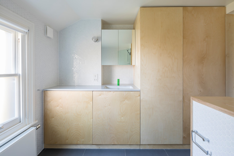 Cette photo montre une grande salle de bain moderne pour enfant avec un placard à porte plane, des portes de placard beiges, une baignoire posée, un combiné douche/baignoire, WC suspendus, un carrelage blanc, des carreaux de céramique, un mur blanc, un sol en carrelage de céramique, un lavabo posé, un plan de toilette en surface solide, un sol gris, une cabine de douche à porte battante, un plan de toilette gris, buanderie, meuble simple vasque, meuble-lavabo encastré et du lambris.