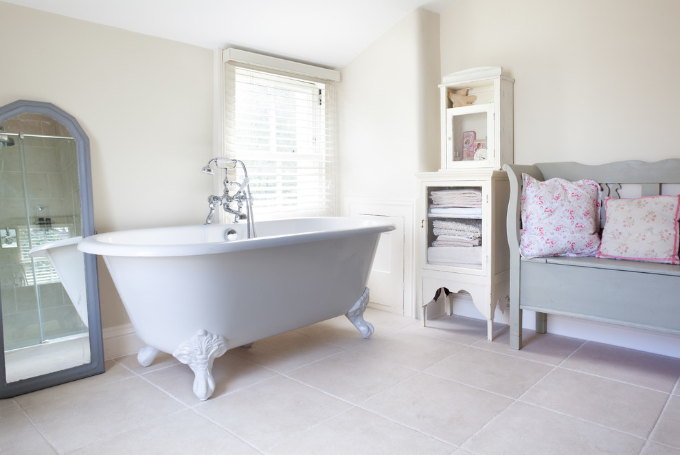 Foto de cuarto de baño principal romántico con puertas de armario blancas, bañera con patas, paredes beige y ventanas