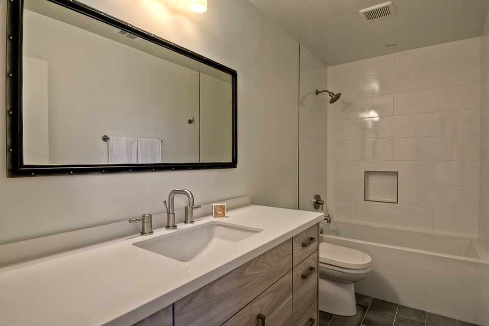 Immagine di una stanza da bagno con doccia moderna con ante lisce, ante in legno chiaro, vasca ad alcova, vasca/doccia, WC monopezzo, piastrelle marroni, piastrelle in gres porcellanato e pareti bianche