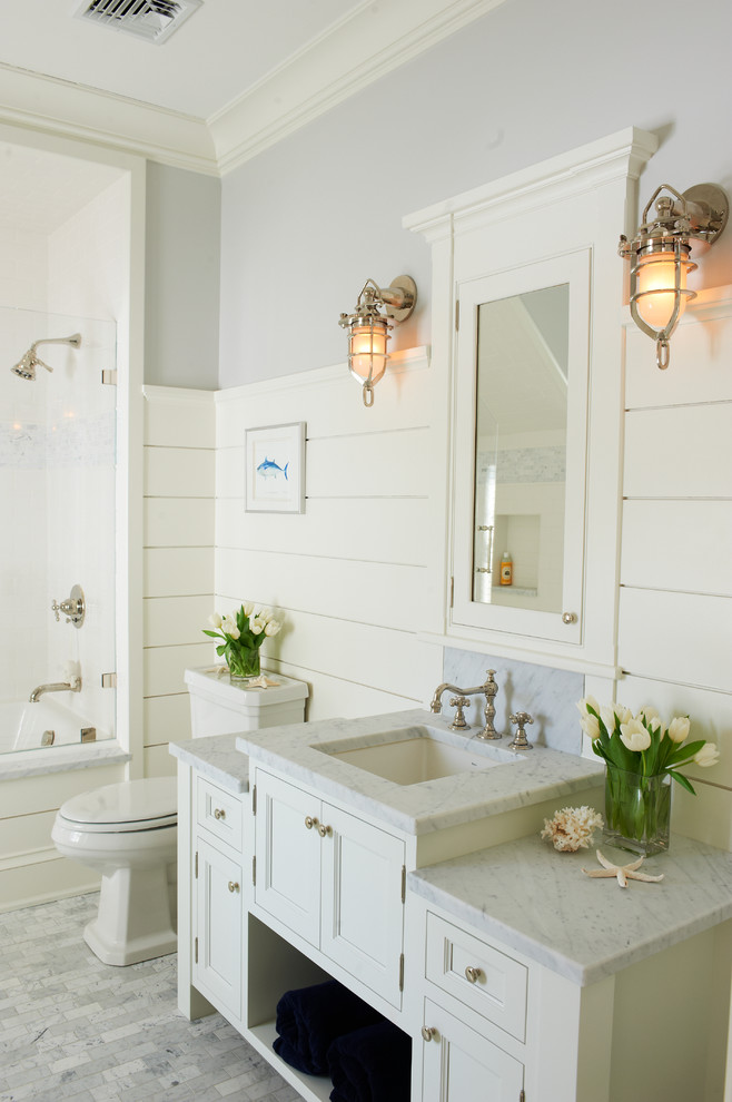 Example of a beach style bathroom design in New York with recessed-panel cabinets, white cabinets, white walls and an undermount sink