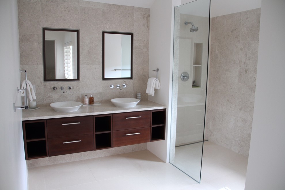 Medium sized world-inspired family bathroom in London with freestanding cabinets, dark wood cabinets, a walk-in shower, a wall mounted toilet, white tiles, ceramic tiles, beige walls and limestone flooring.