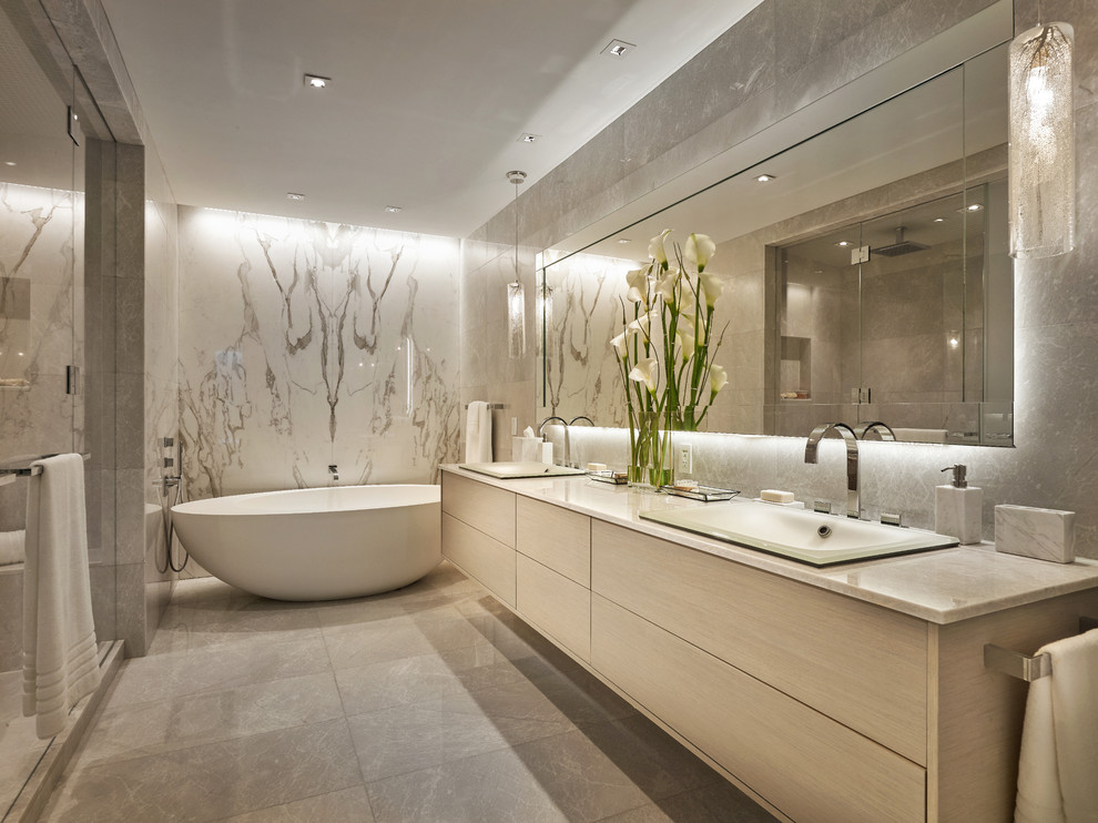 Réalisation d'une salle de bain principale design en bois clair avec un placard à porte plane, une baignoire indépendante et un lavabo posé.
