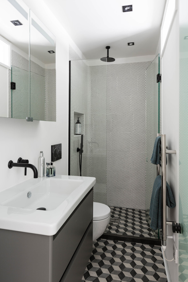 Kleines Modernes Badezimmer En Suite mit flächenbündigen Schrankfronten, grauen Schränken, offener Dusche, Wandtoilette, weißer Wandfarbe, Wandwaschbecken, buntem Boden und Falttür-Duschabtrennung in London