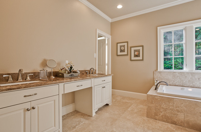 Cette photo montre une grande salle de bain principale chic avec un placard avec porte à panneau encastré, des portes de placard blanches, une baignoire posée, un mur beige et un lavabo encastré.