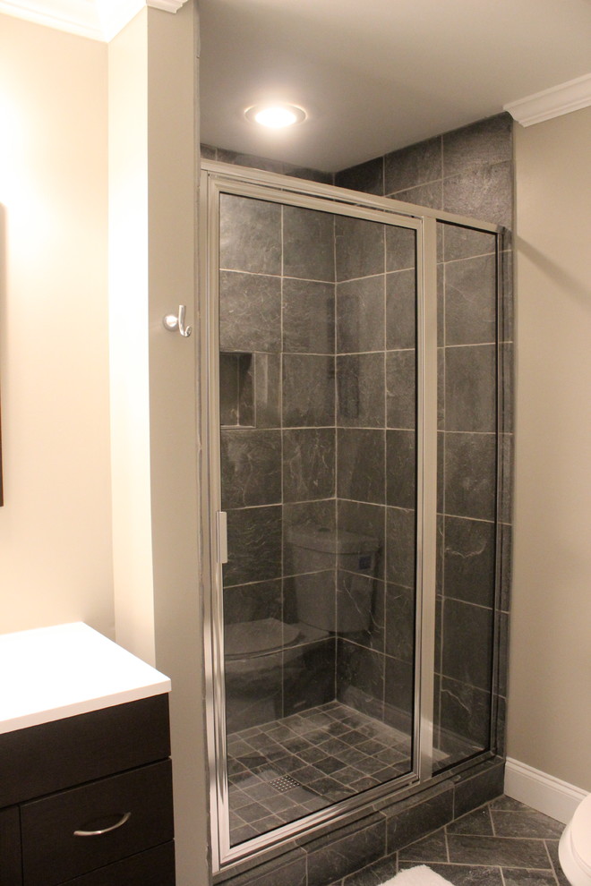 Inredning av ett modernt mellanstort badrum med dusch, med ett integrerad handfat, släta luckor, skåp i mörkt trä, bänkskiva i kvarts, en öppen dusch, en toalettstol med hel cisternkåpa, grå kakel, stenkakel, bruna väggar och skiffergolv