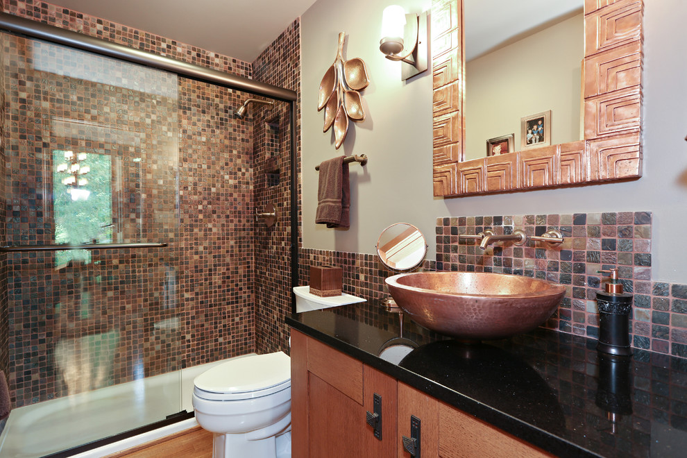 На фото: ванная комната среднего размера в стиле ретро с фасадами цвета дерева среднего тона, ванной в нише, душем над ванной, унитазом-моноблоком, разноцветной плиткой, плиткой мозаикой, бежевыми стенами, полом из керамической плитки, настольной раковиной, столешницей из гранита, разноцветным полом, душем с раздвижными дверями, черной столешницей, встроенной тумбой, потолком с обоями, обоями на стенах, фасадами островного типа, душевой кабиной, тумбой под одну раковину и зеркалом с подсветкой