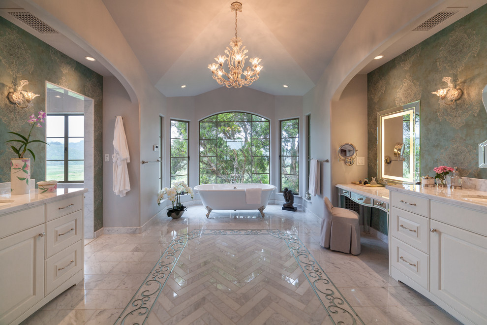 Пример оригинального дизайна: большая главная ванная комната в средиземноморском стиле с фасадами с выступающей филенкой, белыми фасадами, зелеными стенами, врезной раковиной, ванной на ножках, мраморным полом, серым полом, серой столешницей и зеркалом с подсветкой