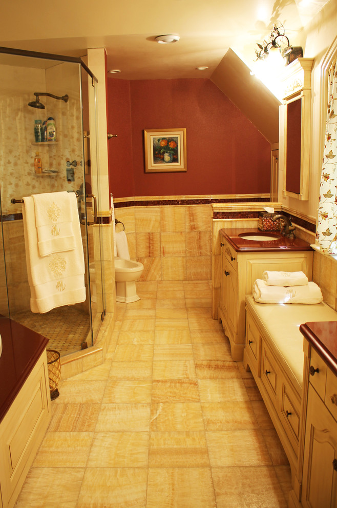 Example of a large tuscan master stone tile and brown tile porcelain tile bathroom design in New York with shaker cabinets, a two-piece toilet, beige walls, a console sink, brown cabinets and marble countertops